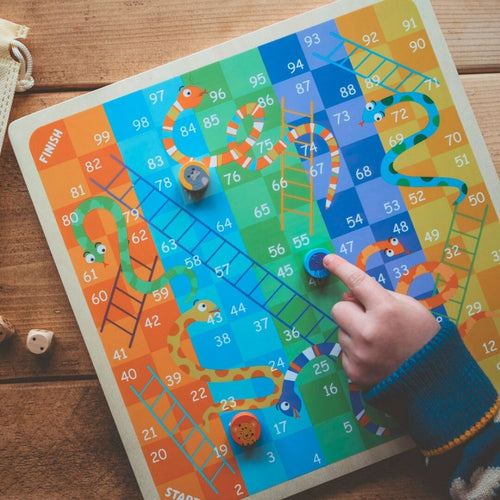  boy moving blue counter playing snakes and ladders 