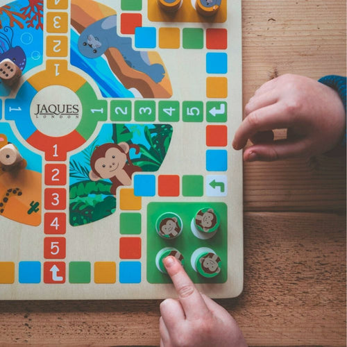  zoom in of boy playing ludo with his green counters set up on the corner of the board 