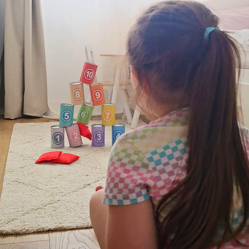 Child playing with colourful number skittles on a carpeted floor. 