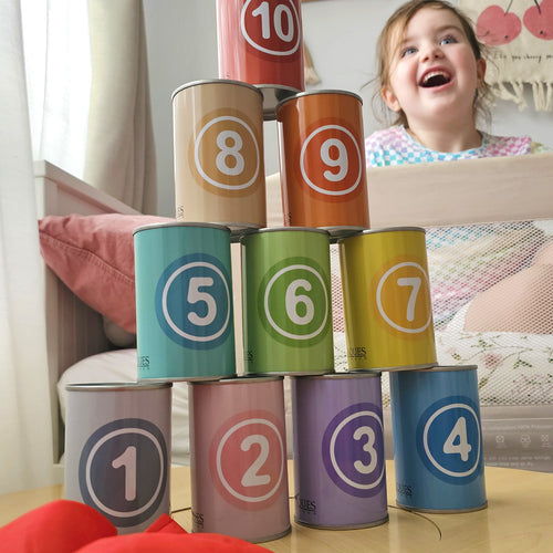 Child playing with number-themed cans stacked in a pyramid 