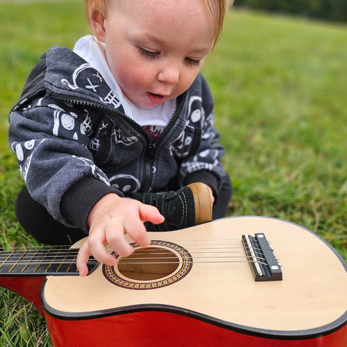 Child playing mini guitar on the grass  