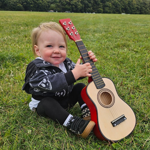 Child holding mini guitar on the grass 