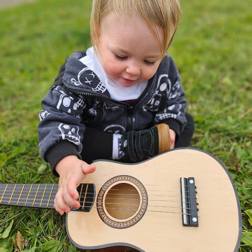 Close up image of child holding mini guitar on the grass 