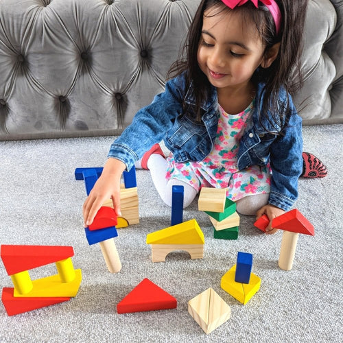 Child playing with tower created with colourful wooden blocks 