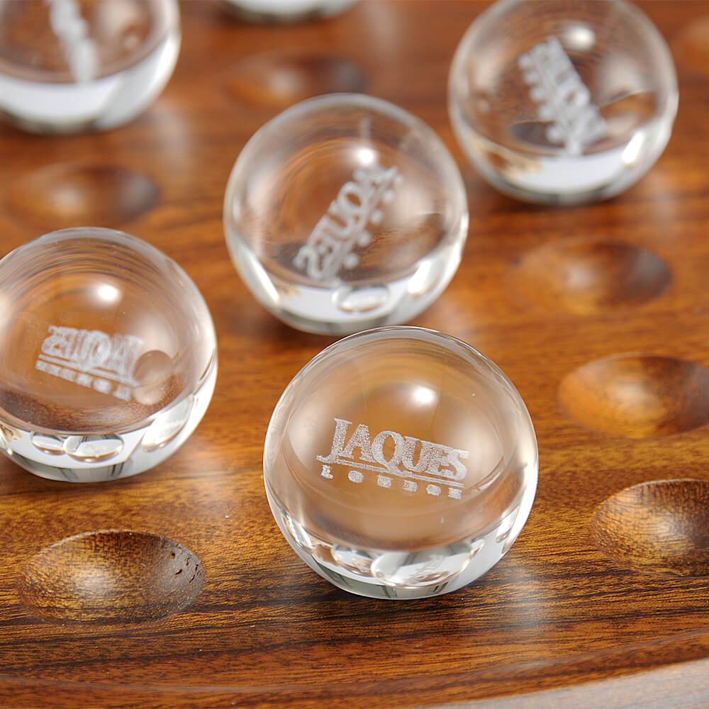  zoomed in image of clear balls with Jaques London written on them  sitting on brown solitaire board.