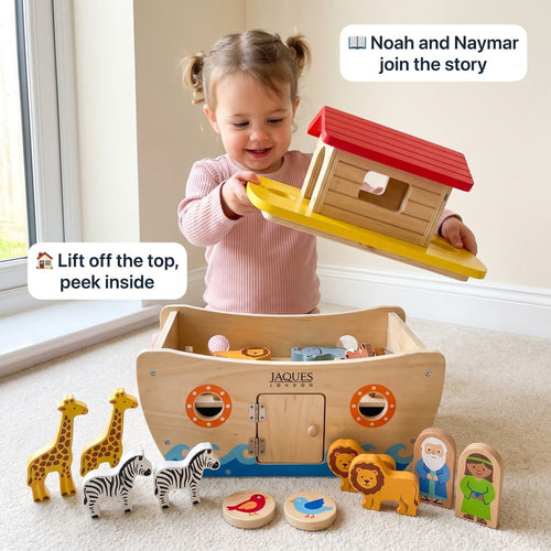 Toddler lifting the whole top off the Jaques wooden Noah’s Ark to peek inside, with Noah and Naymar figures and animals beside it 