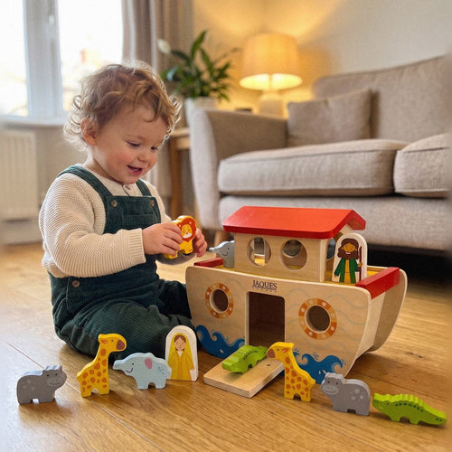 Toddler playing happily with the Jaques wooden Noah's Ark and its chunky wooden animals on a living room floor 