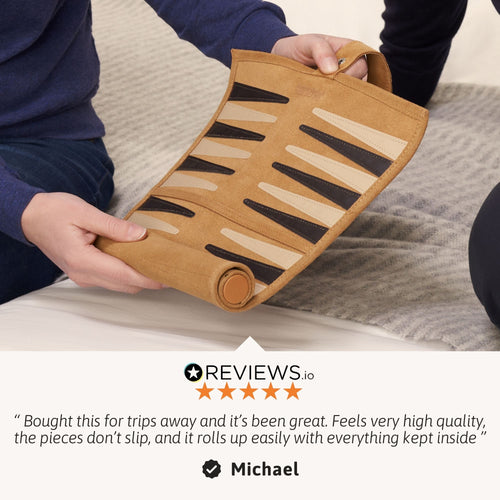 Person holding a rolled-up mat with geometric pattern, sitting on a bed. 