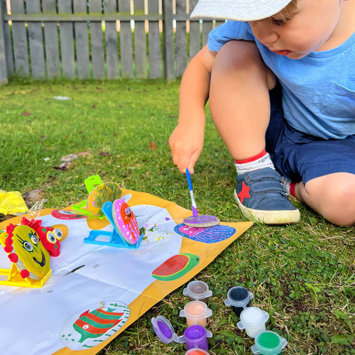  Boy painting rocks with purple paint 