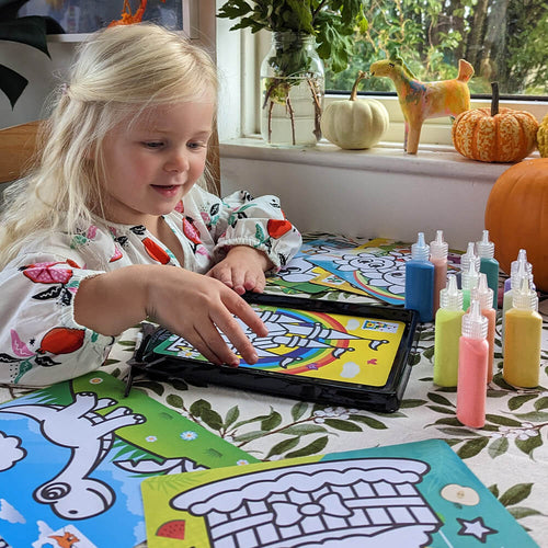  image of girl playing with the sand art set at table 