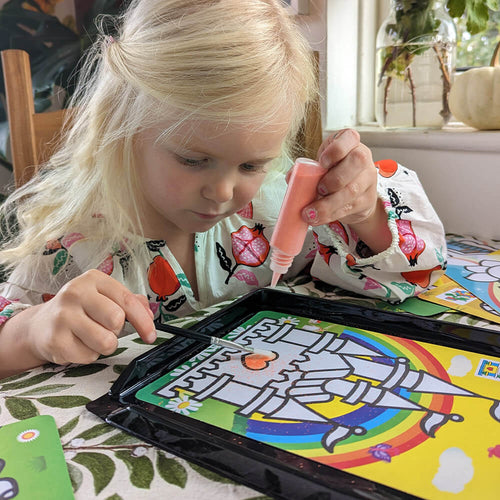  close up of girl playing with the sand art set on table 