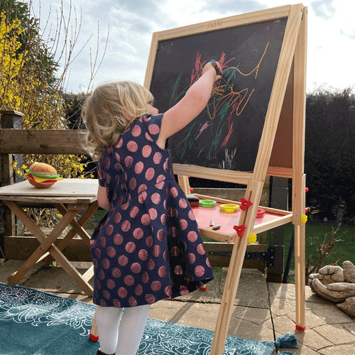  Children's art easel - Girl in garden drawing with chalk on blackboard side of easel.  