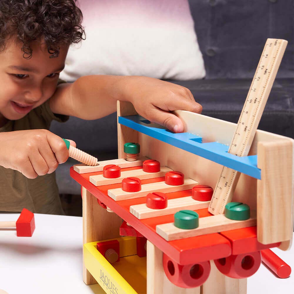 Child putting screw through hole of wooden construction bench  