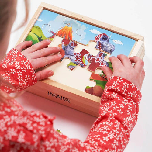  Child making dinosaur jigsaw puzzle on wooden storage box  