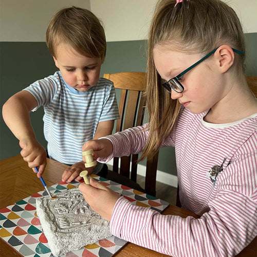   two kids playing with the dinosaur dig kit
