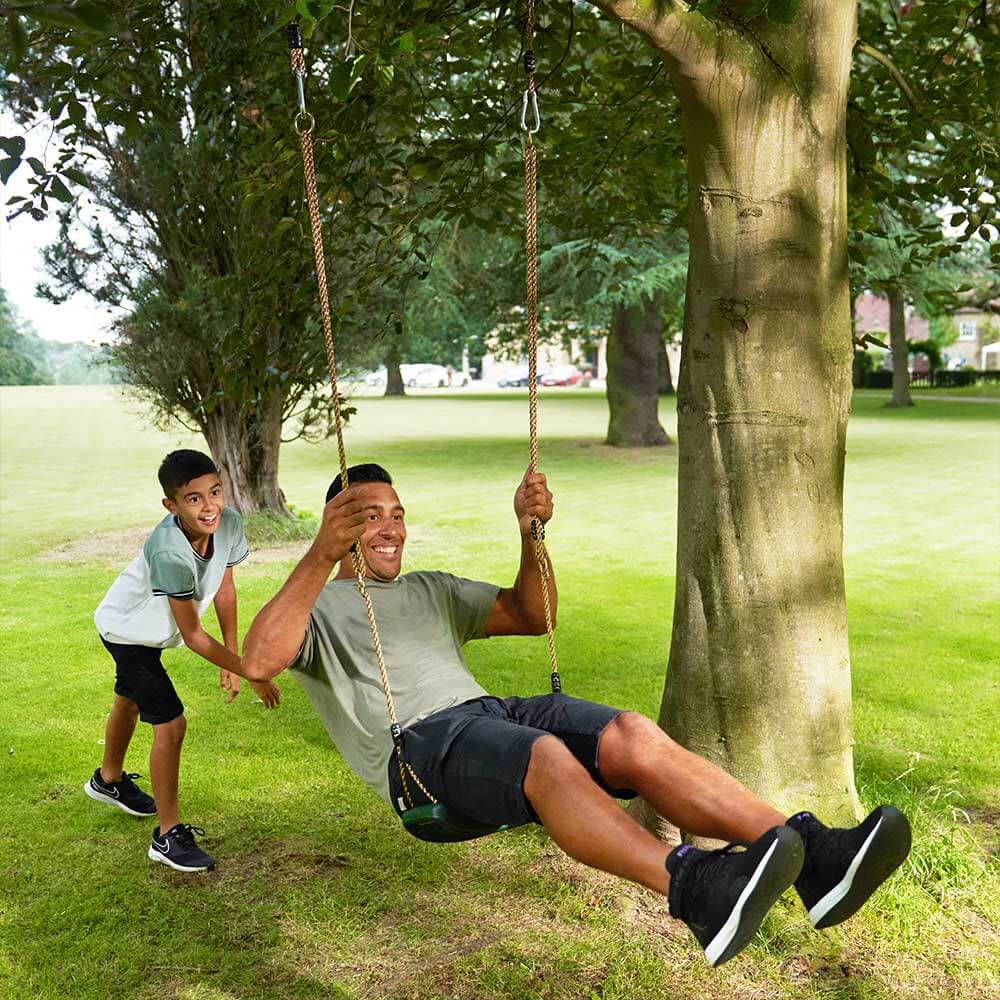 Child pushing adult on garden swing seat 