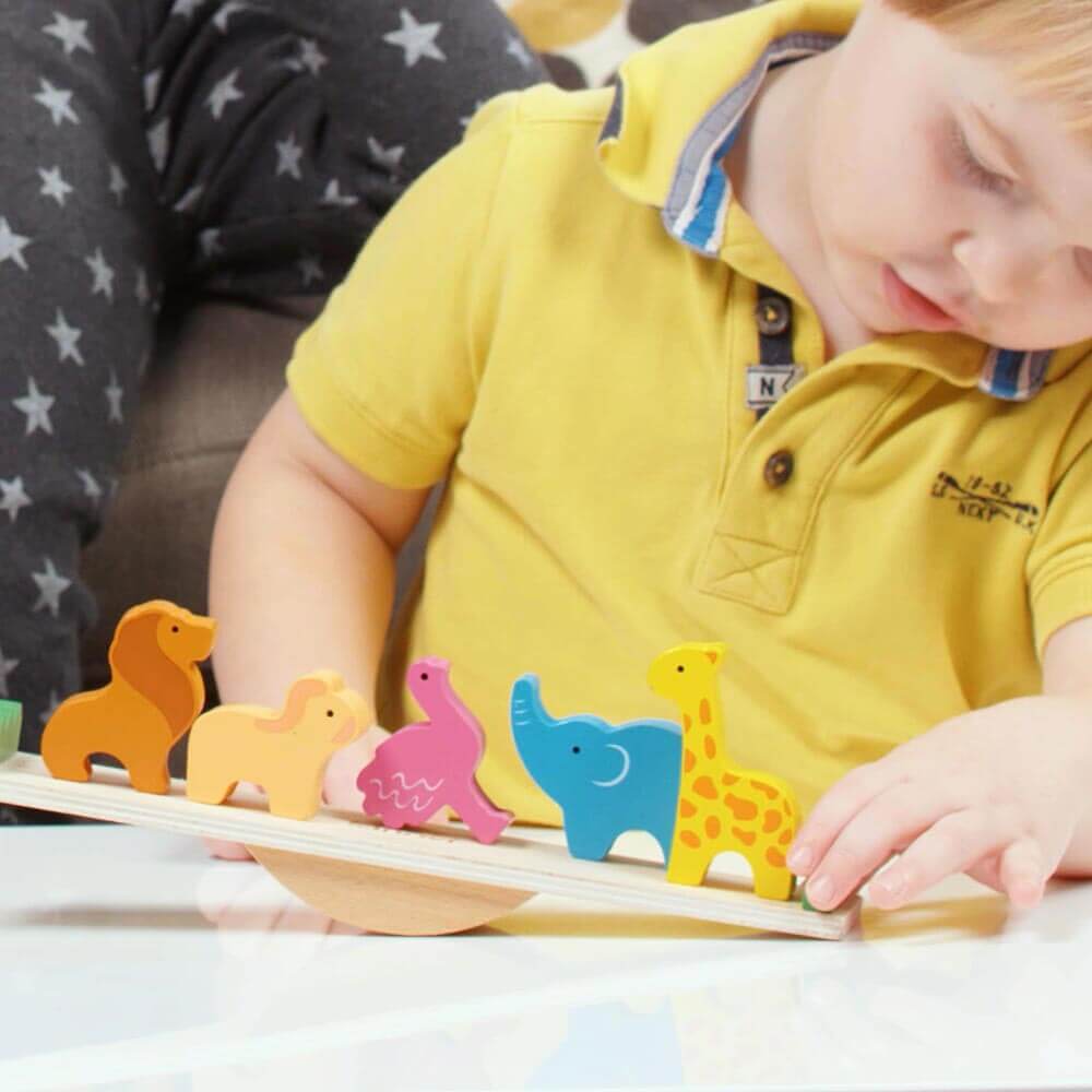  Child playing with wooden seesaw and animals