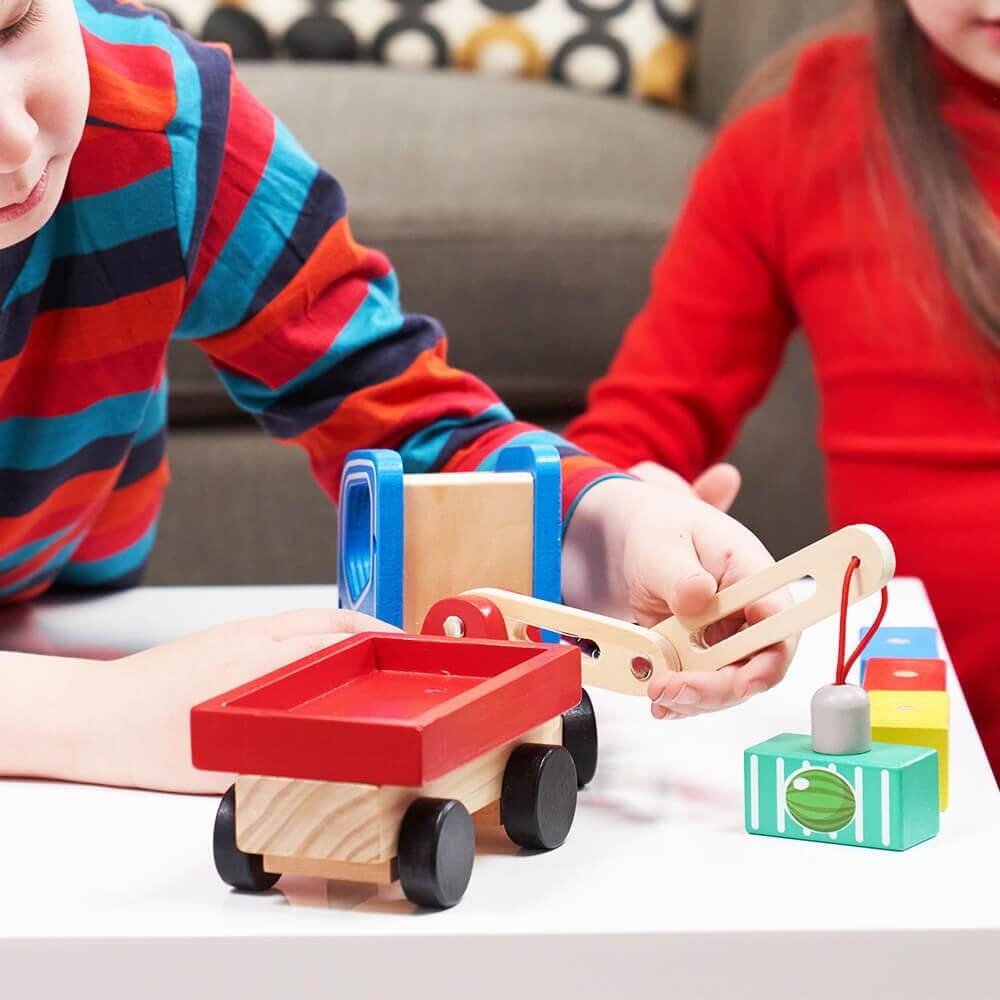  Child using magnetic arm of toy vehicle to lift cargo of watermelons