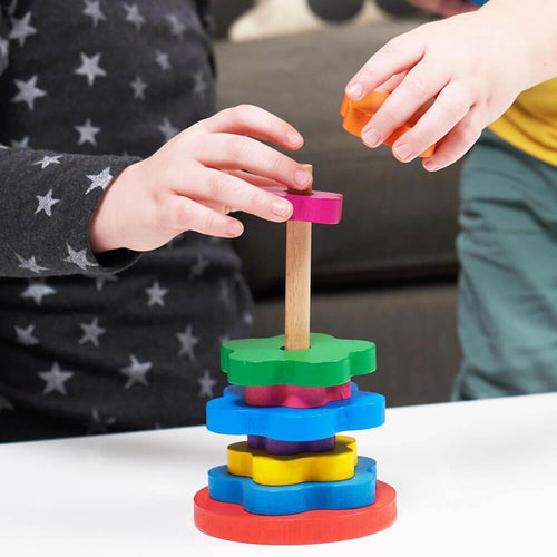 Kids hands sorting rainbow flower shapes on wooden stand  