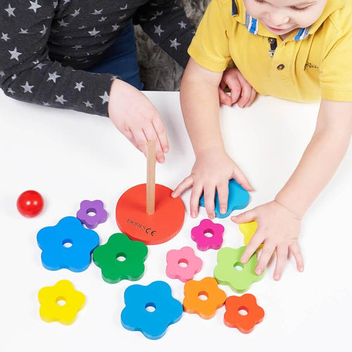 Children sorting wooden rainbow flower shapes to be stacked on stand   