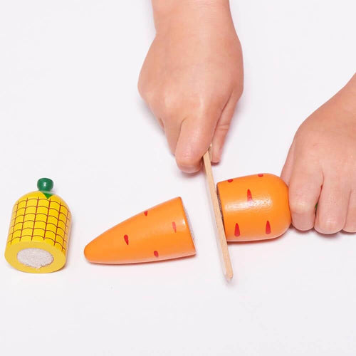 Child cutting carrot with wooden knife  