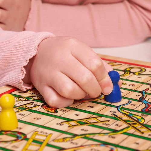  Child moving blue counter on snakes and ladders board game
