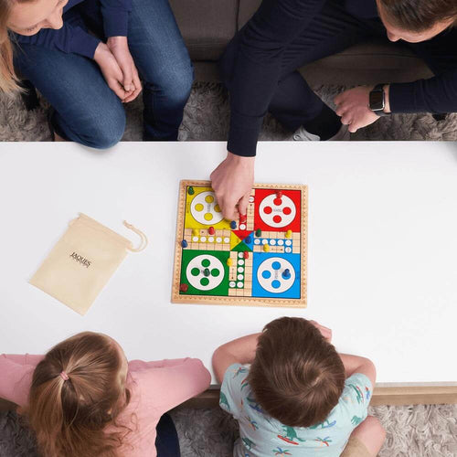  Family playing ludo board game on reversible snakes and ladders 