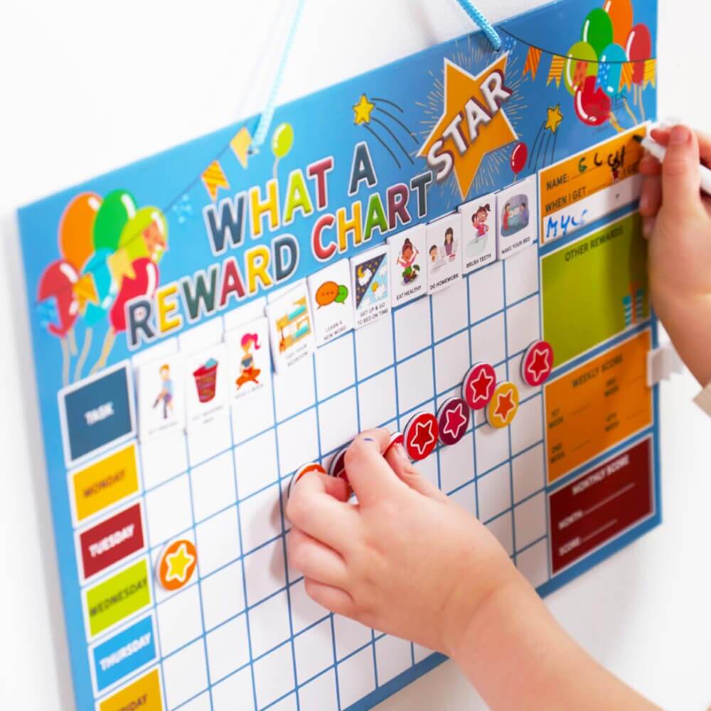  Children placing magnets and writing on star reward chart 